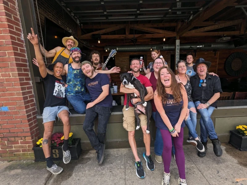 Group of people posing and dog in front of the Speakeasy in Carrboro