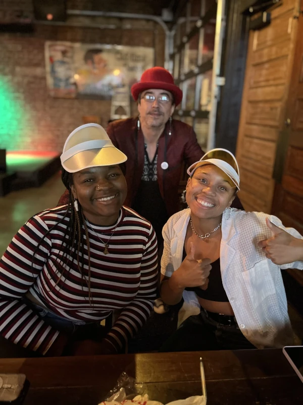 Three people smiling for the camera at the bar in Speakeasy at Carrboro
