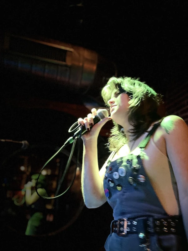 Woman on stage bathed in green light singing at Speakeasy in Carrboro