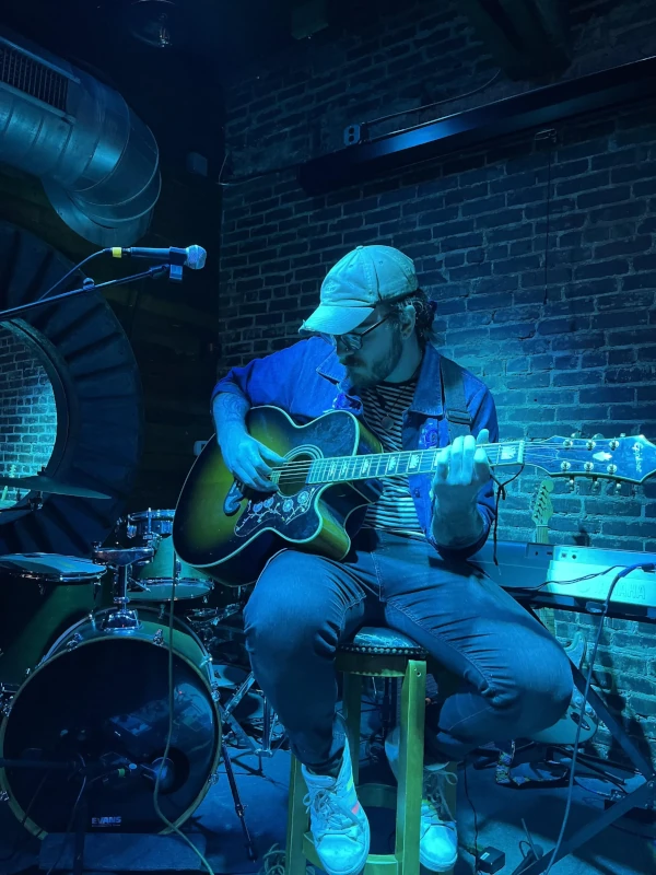 Man playing guitar on stage surrounded by blue light