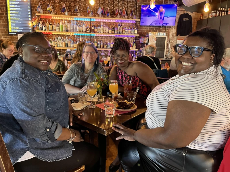 Four women enjoying drinks and a meal at Speakeasy